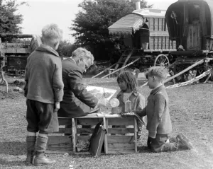 People Prints: Gypsy children watching a man painting their caravan camp on Epsom Downs, Surrey