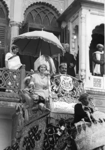 H. M. Queen Elizabeth II rides on an elephant through the streets of Benares, leaving