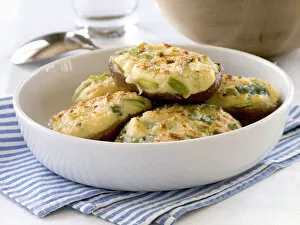 Bowl Collection: Halved baking potatoes baked with topping of cheese and spring onions credit: Marie-Louise