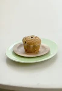 Healthy bran and raisin muffin on small wooden plate on green platter credit: Marie-Louise