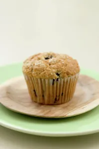 Cooking Prints: Healthy bran and raisin muffin on small wooden plate on green platter credit: Marie-Louise