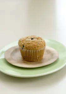 Healthy bran and raisin muffin on small wooden plate on green platter credit: Marie-Louise