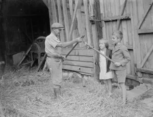 Jimmy Burrows showing flail to children. 1935