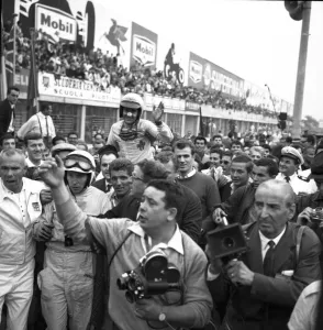 John Surtees and Lorenzo Bandini are mobbed by spectators after the finish of