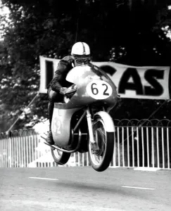1950s Prints: John Surtees MV machine is clear of the ground as he roars over Ballaugh Bridge