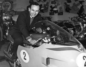John Surtees sitting astride his racing MV Augusta motorbike inside his family motorcycle