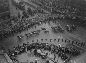 The King and Queen in an open carriage with mounted escort driving through the streets