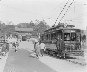 Kyoto island of Honshu, Japan An electric tram in the foreground, with an old gateway
