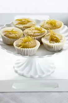Bake Off Inspiration Collection: Lemon muffins with lemon zest glaze on white cakestand credit: Marie-Louise Avery