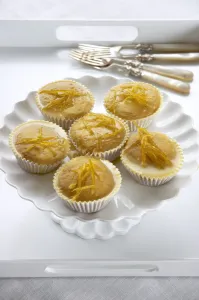 Lemon muffins with lemon zest glaze on white cakestand credit: Marie-Louise Avery