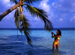 Paradise Prints: Little Bandos, an island ion the Maldives. With girl tugging at a palm tree