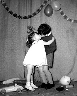 Children Collection: A little boy and girl kissing under the mistletoe at a Christmas party