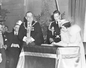 Their Majesties the King and Queen signing the golden Visitors Book at the City Hall