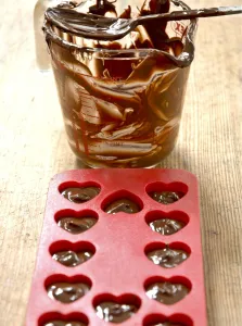Making heart shaped in chocolates for Valentines day in red heart shaped mould