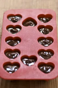 Making heart shaped in chocolates for Valentines day in red heart shaped mould credit