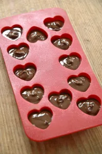 Making heart shaped in chocolates for Valentines day in red heart shaped mould credit