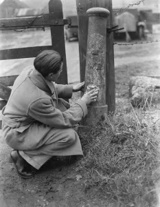 Fence Prints: A man uses a cloth to try and clean a boundary post. 1937