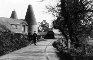 Agriculture Collection: A man walks down a country road passing an oast house, near Penshurst, Kent, England