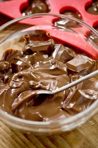 Sweet Prints: Melted chocolate in glass bowl with red heart mould behind credit: Marie-Louise
