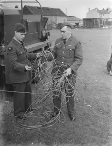 Military Prints: Two men examine storm damage in the form of broken cable at a balloon barrage base