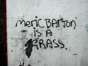 Lifestyle Prints: Meric Barton is a grass: graffiti on the side of a building denouncing a local person