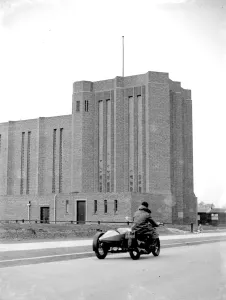 Exterior Prints: A motorcycle riding past St Saviour Church in Eltham, Kent. 1934