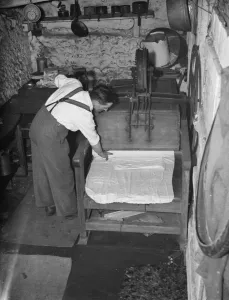 Wood Prints: Mr George goodwin operating an old fashion mangle in Meopham. 1938