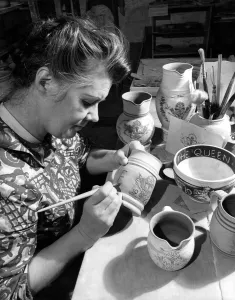 Royals Prints: Mrs Rachel Warner using a brush to apply colour to the decoration engraved on a piece