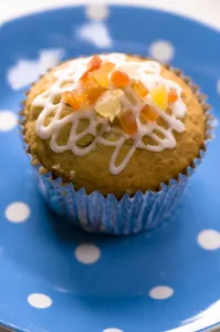 Muffin decorated with squiggly icing and candied peel on spotted blue plate credit