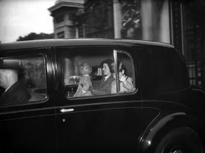 Nurse Helen Lightbody holds Princess Anne, and Prince Charles amuses himself by