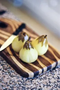 Peeled pears poached in vanilla sugar syrup on striped wooden board credit: Marie-Louise