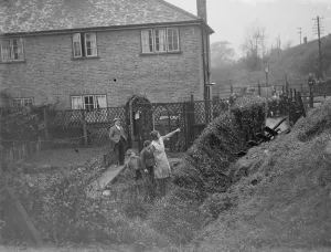 Hedge Prints: People watch from their back gardens as men work to clear the land slide on the Wellhall