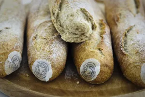 Symbol Prints: Pile of stoneground wholemeal organic baguettes on woden board credit: Marie-Louise