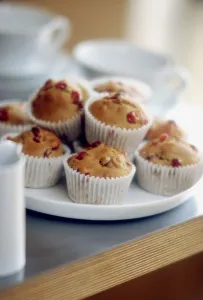 Kitchen Prints: Plate of muffins in paper cases in teatime setting credit: Marie-Louise Avery /