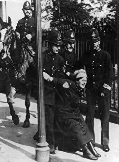 Suffragette Collection: Political - four policemen, one mounted, arrest a suffragette