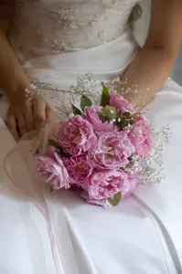 Posy Prints: Posy style bridal bouquet held in hands on white satin dress credit: Marie-Louise