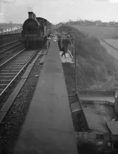 Railway workers stand on a scaffold frame on the edge of the viaduct as a steam engine