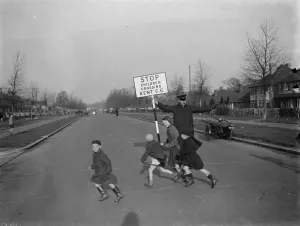 Road attendant from Kent County Council, holding a sign, helps children in St Mary