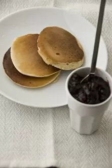 Pile Collection: Three Scotch pancakes on a white plate with small pot of raspberry jam credit