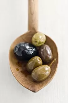 Olive Collection: Selecion of various good whole olives on rustic wooden spoon credit: Marie-Louise
