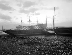 Shipping run aground on the shore in front of HMS Worcester on the River Thames off