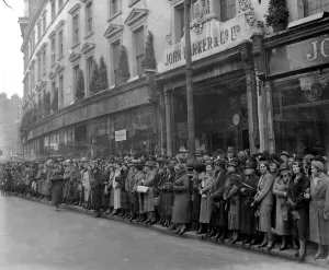 A shopping crowd in Kensington turns its back on the window display to watch
