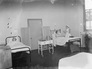 Health Care Prints: The Sidcup Cottage Hospital in Kent. A nurse tends to a patient in the womens ward
