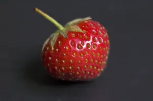 Berry Prints: Single strawberry on a black plate credit: Marie-Louise Avery / thePictureKitchen