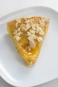 Dessert Prints: Slice of peach cake / tart sprinkled with flaked almonds credit: Marie-Louise Avery