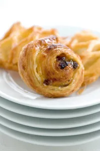 Small danish pastries on stack of white plates credit: Marie-Louise Avery / thePictureKitchen