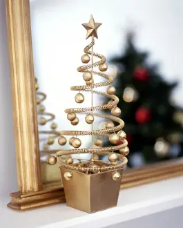 Decorative Prints: Small decorative, gilt abstract christmas tree on mantel shelf with real alrge green