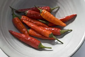 Small hot birds eye chilli peppers arranged on white surface. credit: Marie-Louise