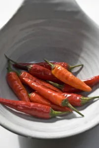 Small hot birds eye chilli peppers arranged on white surface. credit: Marie-Louise