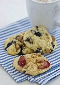 Berry Collection: Soft cookies with berries and nuts on blue and white striped napkin with mug of cappucino credit